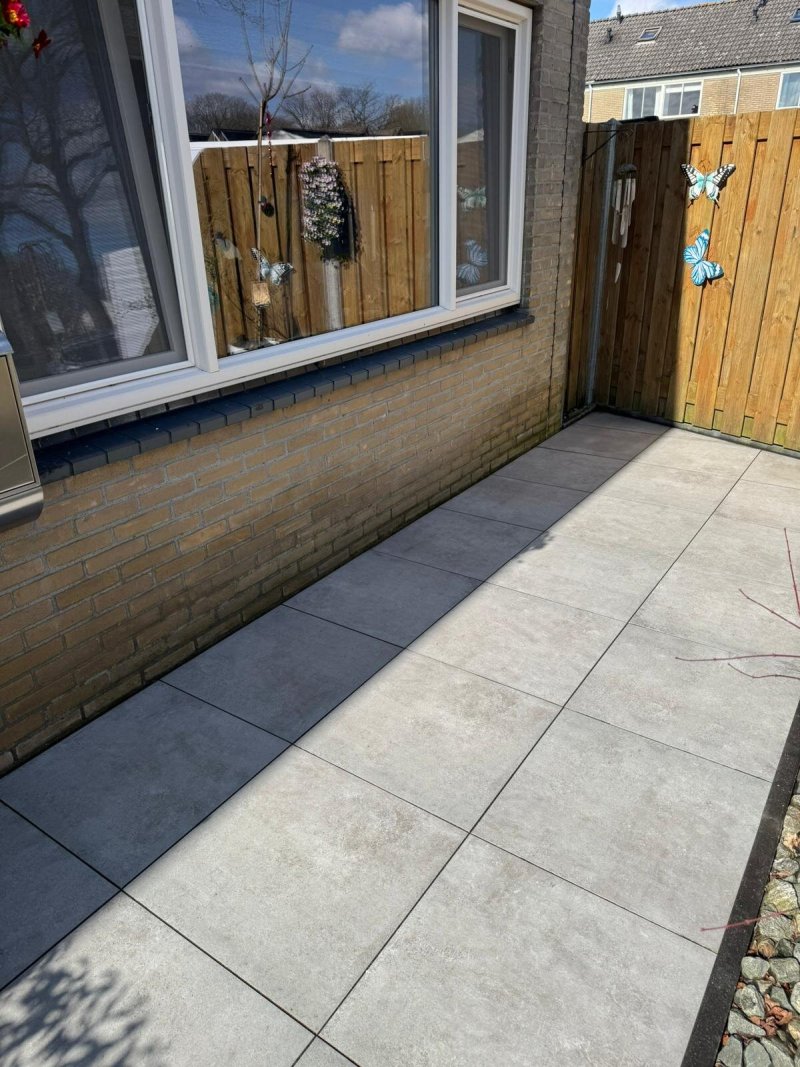 Hetzelfde achterterras na reiniging: de tegels zijn weer licht en egaal